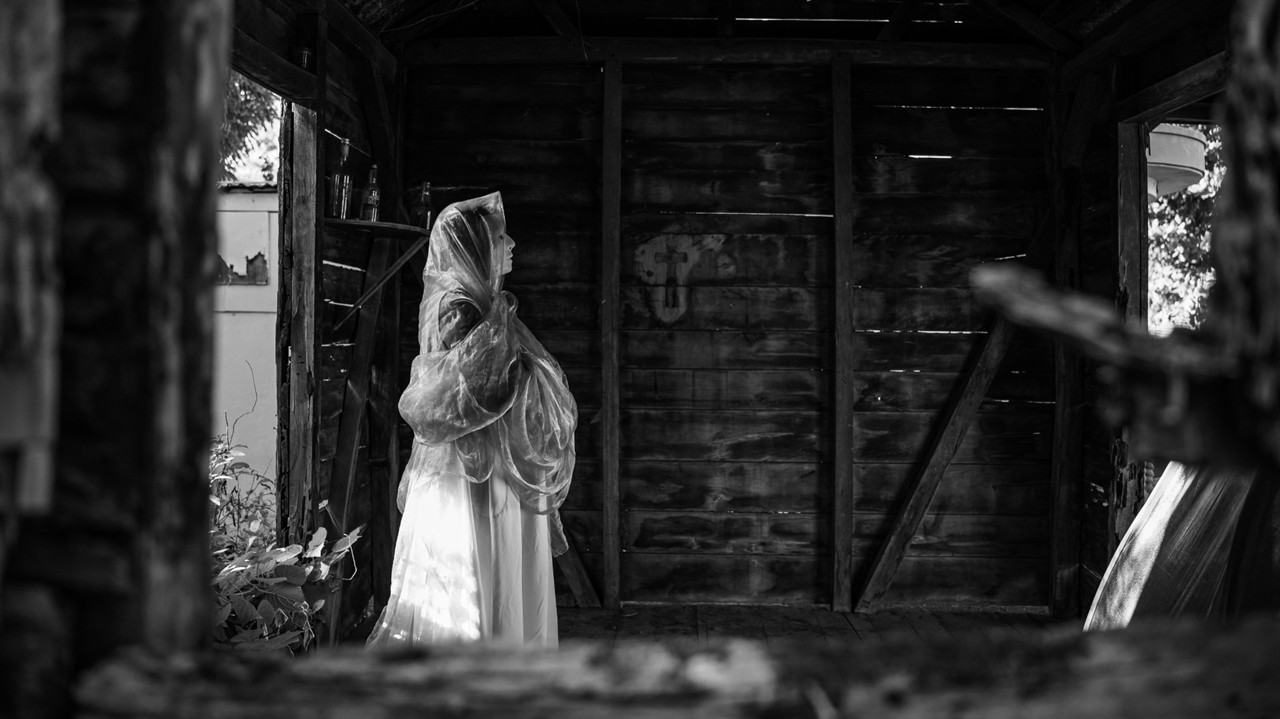 A woman in a headscarf stands in a wooden room